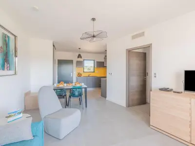 a living room with a dining room table and a kitchen at Apartment Stanatura-4 by Interhome in Porto-Vecchio