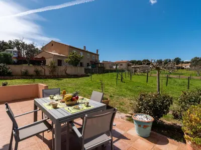 a table and chairs on a patio with a yard at Villa Les Rosiers by Interhome in Porto-Vecchio