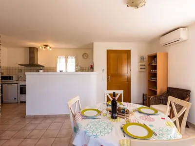 a dining room and kitchen with a table and chairs at Villa Les Rosiers by Interhome in Porto-Vecchio