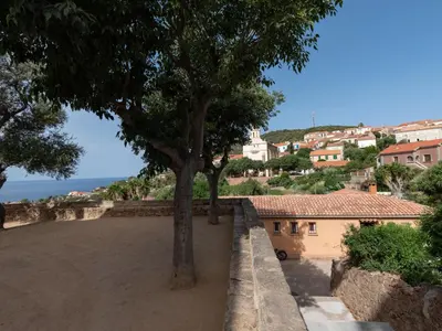 a tree on the side of a wall with a city at Apartment La Spelunca by Interhome in Cargèse