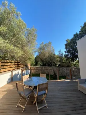 a patio with a table and chairs on a wooden deck at Mini-Villa Jade in Bonifacio