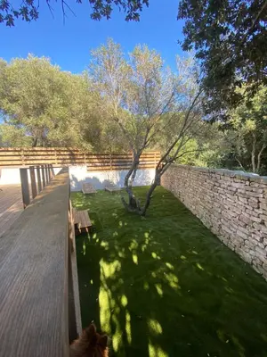 a dog is sitting on a deck next to a brick wall at Mini-Villa Jade in Bonifacio