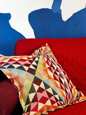 a colorful pillow sitting on top of a red couch at Campo Vecchio Dracena et Piscine in Ghisonaccia