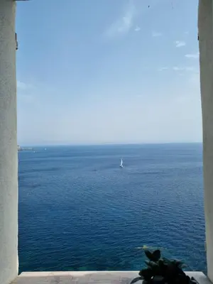 a window view of the ocean with a sailboat in the water at Mare è rocca in Bonifacio
