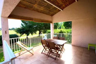 a patio with a table and chairs on a balcony at Campo Vecchio Kamerops et piscine in Ghisonaccia