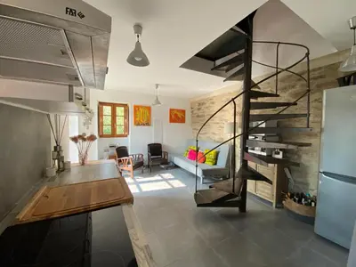 a kitchen and a living room with a spiral staircase at Les Canali in Santo-Pietro-di-Tenda