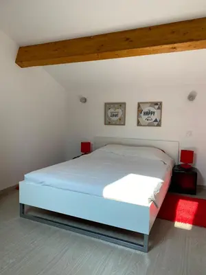 a white bed in a room with two pictures on the wall at Les Canali in Santo-Pietro-di-Tenda