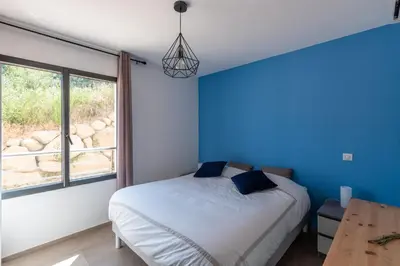 a bedroom with a bed and a blue wall at L'Aurore de Cruciata - Appt vue baie d'Ajaccio in Pietrosella