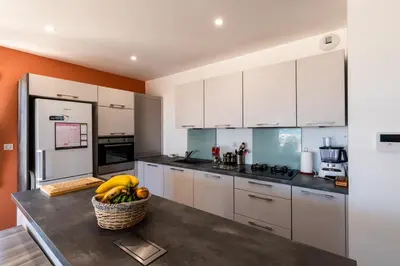 a kitchen with white cabinets and a basket of bananas on a table at L'Aurore de Cruciata - Appt vue baie d'Ajaccio in Pietrosella