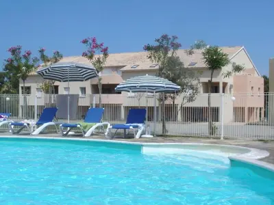 a swimming pool with chairs and umbrellas at Appartement T2 dans résidence avec piscine in Moriani Plage