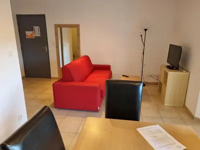 a living room with a red chair and a television at Appartement T2 dans résidence avec piscine in Moriani Plage