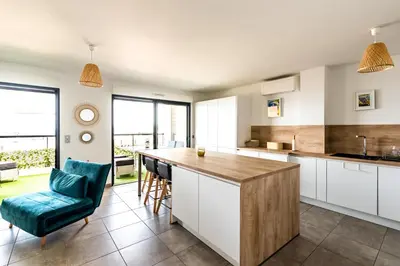 a kitchen with white cabinets and a blue chair at L'étincelle de Stagnola - Vue mer in Pietrosella