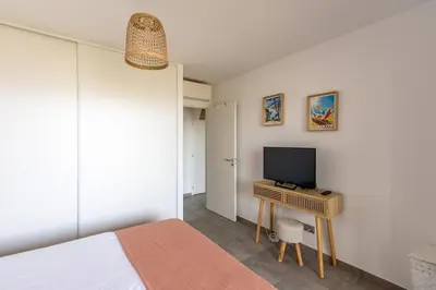 a bedroom with a bed and a desk with a television at L'étincelle de Stagnola - Vue mer in Pietrosella