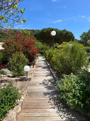 a wooden path through a garden with flowers and lights at Les Jardins De Santa Giulia - Charmante chambre dhte 1 in Porto-Vecchio