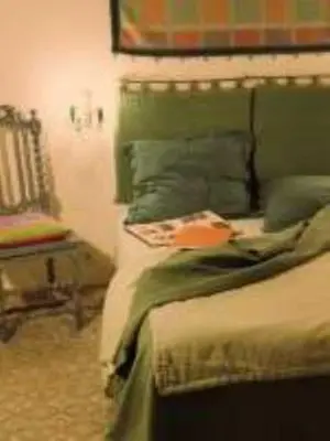 a bedroom with a bed with a green headboard and a chair at Hôtel Restaurant L'Aiglon in Zonza