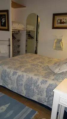 a bedroom with a bed with a blue and white blanket at Hôtel Restaurant L'Aiglon in Zonza