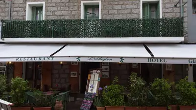 a building with a balcony and a hotel at Hôtel Restaurant L'Aiglon in Zonza