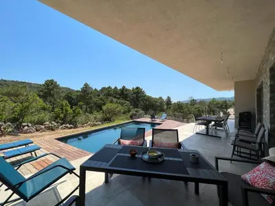 a patio with a table and chairs and a swimming pool at Villa Monte e Mare, piscine chauffée, climatisée à 5 mn de la plage de santa giulia in Porto-Vecchio