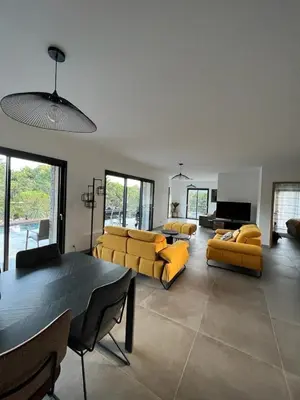 a living room with yellow couches and a table at Villa Monte e Mare, piscine chauffée, climatisée à 5 mn de la plage de santa giulia in Porto-Vecchio
