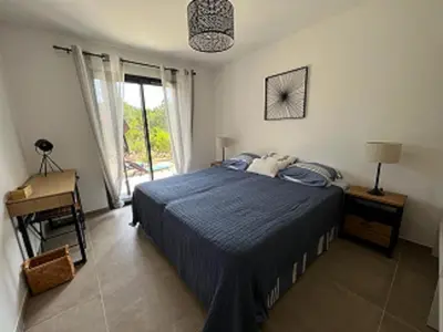 a bedroom with a blue bed and a window at Villa Monte e Mare, piscine chauffée, climatisée à 5 mn de la plage de santa giulia in Porto-Vecchio