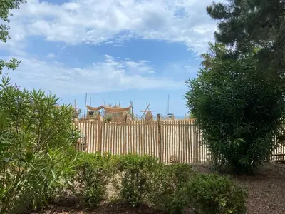 a wooden fence in front of a fence with nets on it at Les Lodges de la Plage U Dragulinu in Sari Solenzara