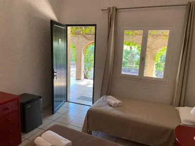 a bedroom with two beds and a door to a room at Les Lodges de la Plage U Dragulinu in Sari Solenzara