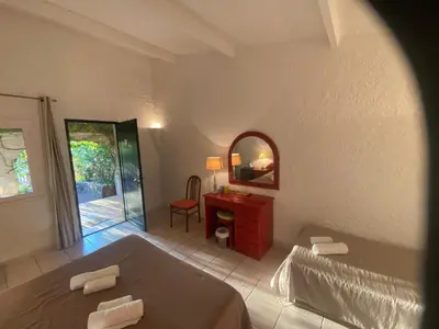 a bedroom with a bed and a table and a mirror at Les Lodges de la Plage U Dragulinu in Sari Solenzara