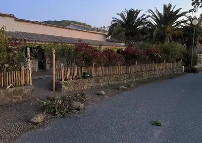 a fence in front of a house with plants at Les Lodges de la Plage U Dragulinu in Sari Solenzara