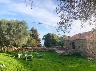 a yard with tables and chairs and a stone building at Domaine de la Coletta Maison traditionnelle in Coti-Chiavari