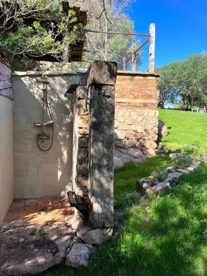 a stone pillar in the grass next to a building at Domaine de la Coletta Maison traditionnelle in Coti-Chiavari