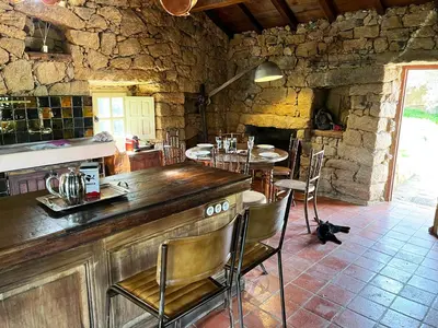 a kitchen with a counter and tables and chairs at Domaine de la Coletta Maison traditionnelle in Coti-Chiavari