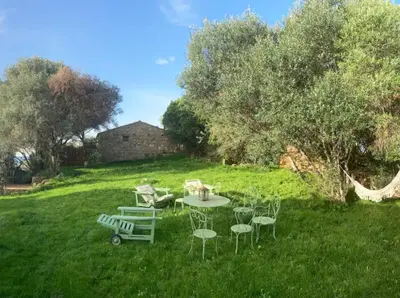 a table and chairs in the grass in a field at Domaine de la Coletta Maison traditionnelle in Coti-Chiavari