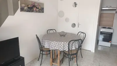 a kitchen with a table and chairs in a room at Maison à 200m de la mer, 10 mn de l'aéroport de Bastia et a 20mn du port in Lucciana