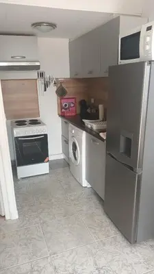 a kitchen with a refrigerator and a washing machine at Maison à 200m de la mer, 10 mn de l'aéroport de Bastia et a 20mn du port in Lucciana