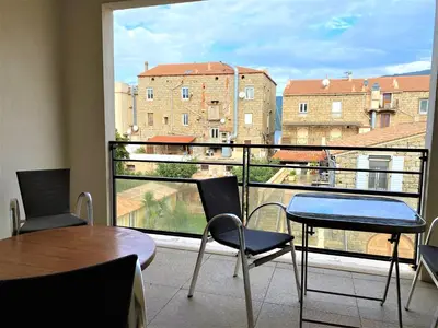 a balcony with a table and chairs and a large window at PORTO PIANO 2 pièces en centre-ville in Propriano