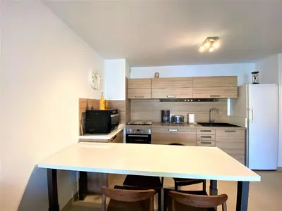 a kitchen with a table and a refrigerator at PORTO PIANO 2 pièces en centre-ville in Propriano