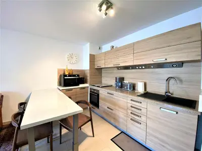 a kitchen with wooden cabinets and a white table at PORTO PIANO 2 pièces en centre-ville in Propriano