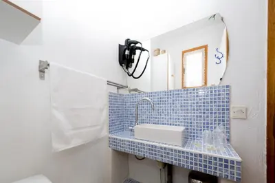 a blue tiled bathroom with a sink and a mirror at Appartements A Merendella in Serriera