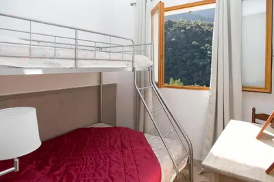 a bedroom with a bunk bed with a red bedspread at Appartements A Merendella in Serriera