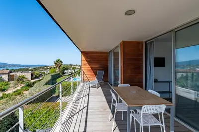 a balcony with a wooden table and chairs at Via Mare - Apt avec splendide vue in Grosseto-Prugna
