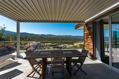 a patio with a wooden table and chairs on a balcony at Via Mare - Apt avec splendide vue in Grosseto-Prugna