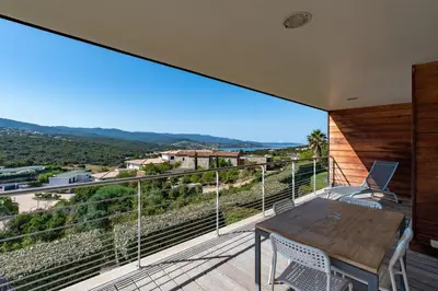 a large balcony with a wooden table and chairs at Via Mare - Apt avec splendide vue in Grosseto-Prugna