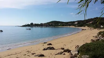 a sandy beach with a boat in the water at Mare E Monti in Porto Pollo