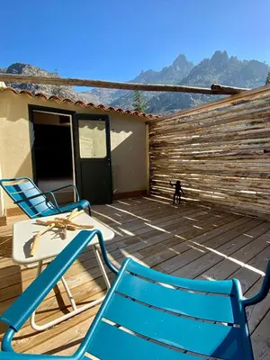 a deck with two chairs and a table and a dog at Hôtel Domaine A Flatta in Calenzana
