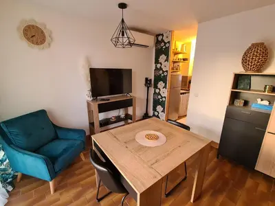 a living room with a wooden table and a blue chair at Studio avec terasse vue mer in Porticcio