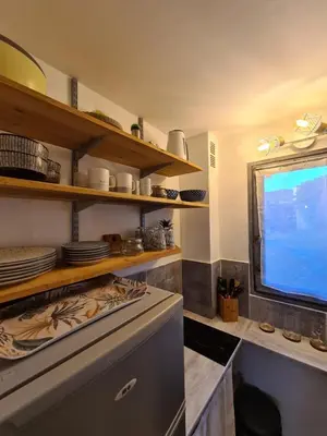 a kitchen with a tv and a stove and shelves at Studio avec terasse vue mer in Porticcio