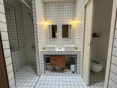a white tiled bathroom with two sinks and a toilet at Appartement de maître T3 80m2 en plein centre. in Ajaccio