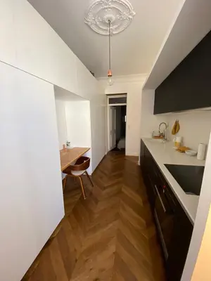 a kitchen with white counters and a wooden floor at Appartement de maître T3 80m2 en plein centre. in Ajaccio