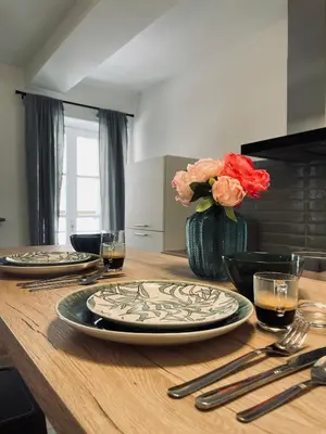 a wooden table with two plates and a vase with flowers at Superbe appartement T2 en plein centre d'Ajaccio, rue Fesch in Ajaccio