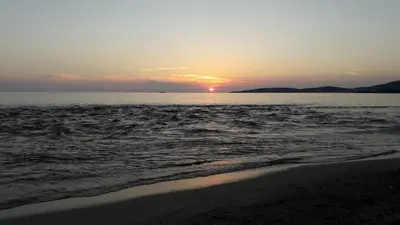 a sunset over the ocean with a beach with at chalets bois 150m de la plage in Olmeto